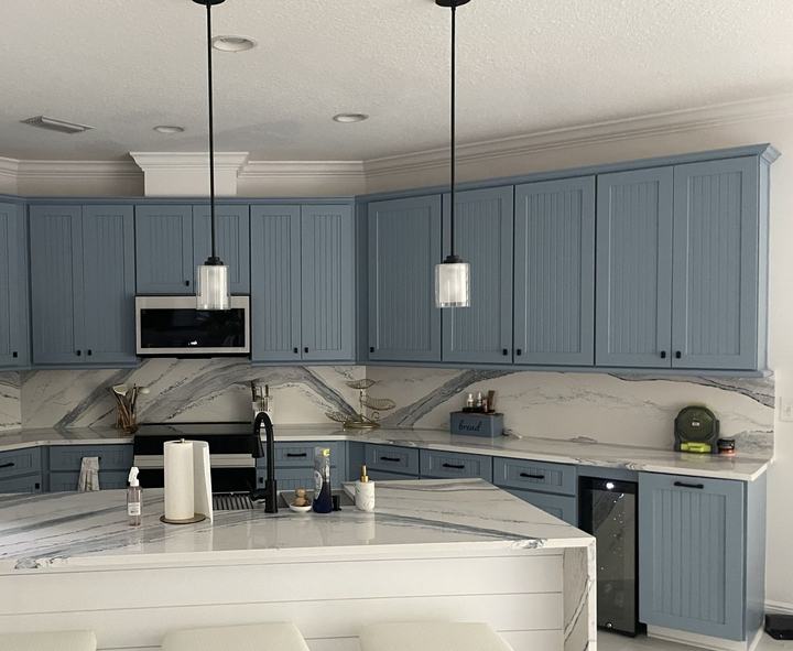 Blue cabinets, full-height slab backsplash and waterfall island