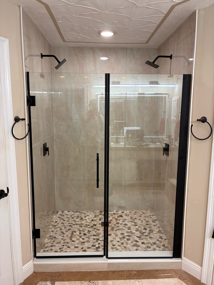 Walk-in shower with black-framed glass, dual rain heads and pebble floor