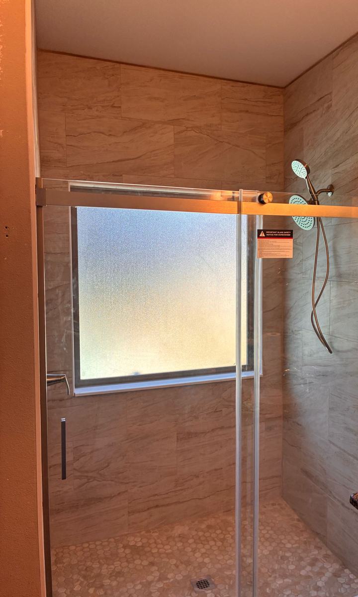 Cream tile shower with glass door, another angle