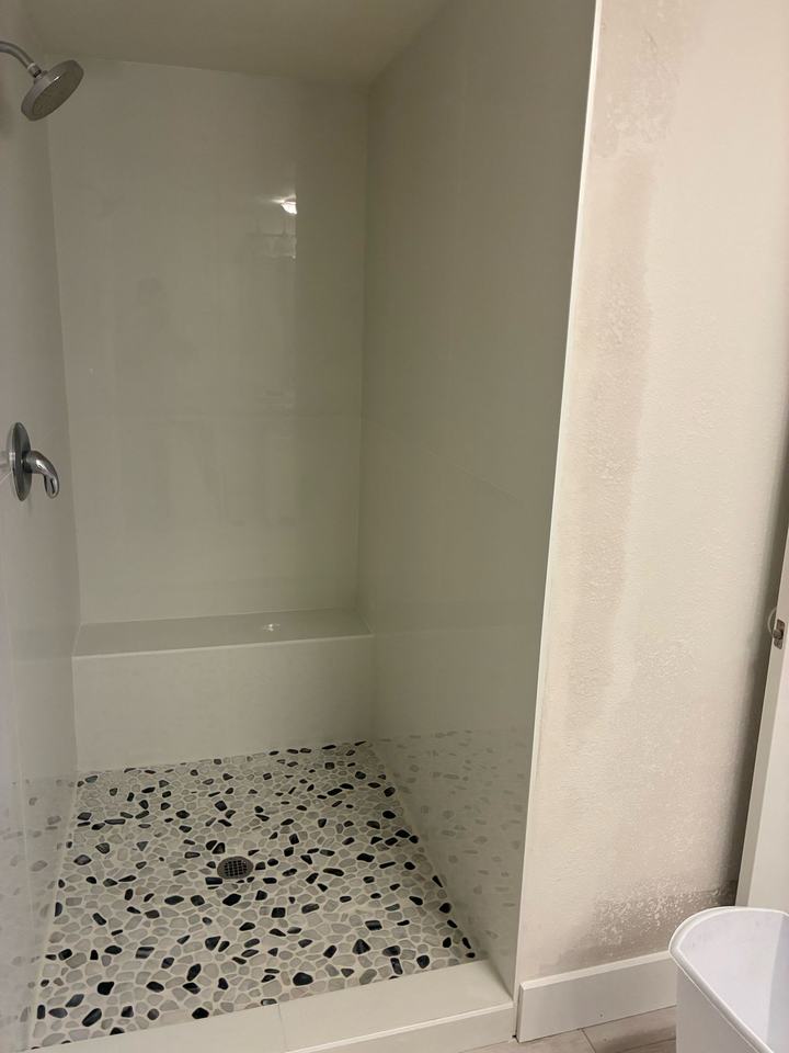 White tile shower with bench and pebble floor